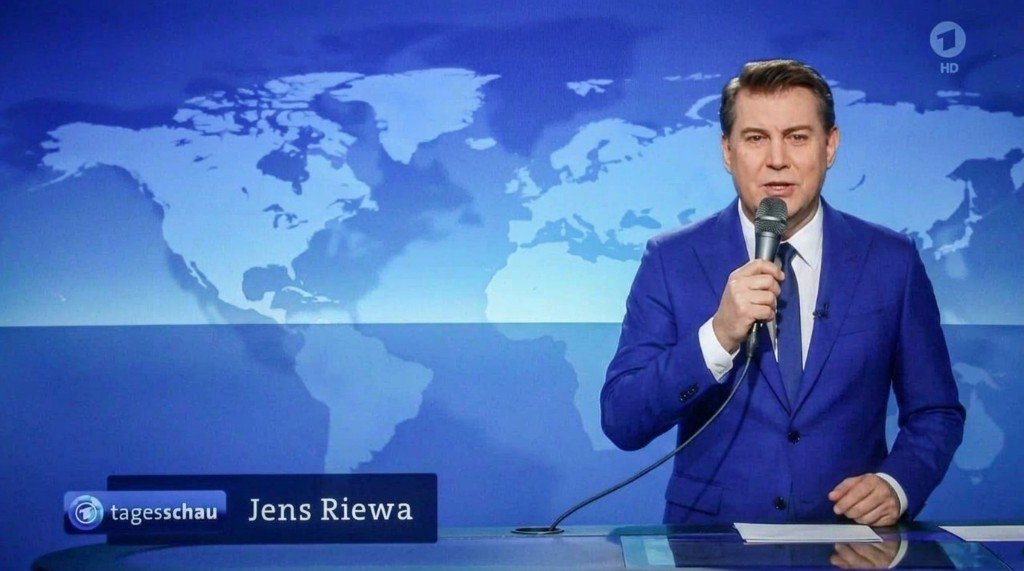 Jens Riewa im Nachrichtenset mit einem kabelgebundenen Handmikrofon